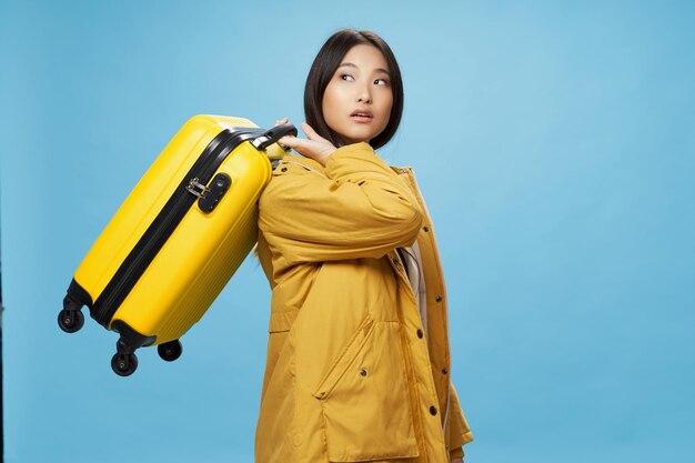 Vrouw aziatische verschijning gele koffer vakantie reizen blauwe achtergrond