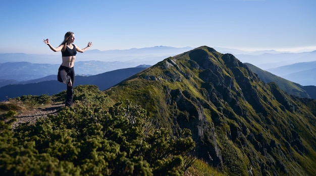Vrouw balanceert op één been in de bergen