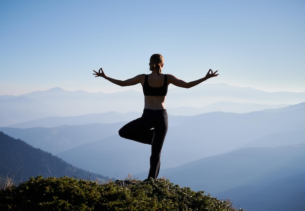 Vrouw balanceert op één been in de bergen