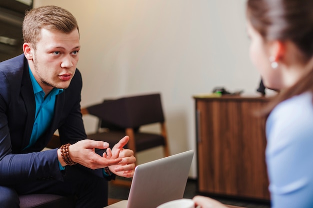 Gratis foto vrouw bedrijf beker en man zitten praten