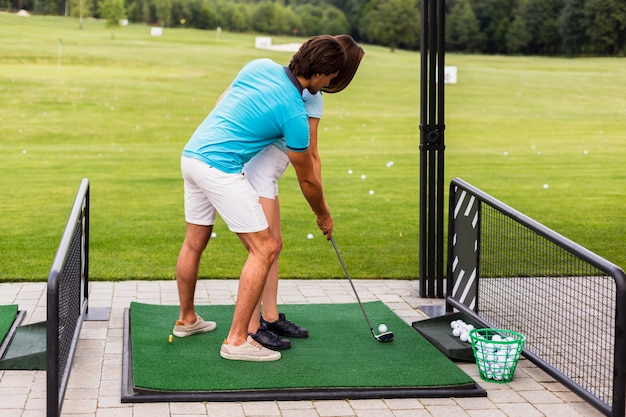 Vrouw beoefenen van golfbewegingen met trainer