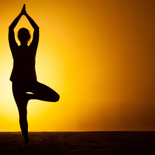 Vrouw beoefenen van yoga in het zonsonderganglicht