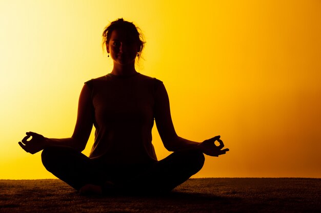 Vrouw beoefenen van yoga in het zonsonderganglicht