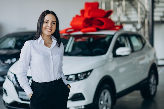 Vrouw bij de auto met grote rode strik