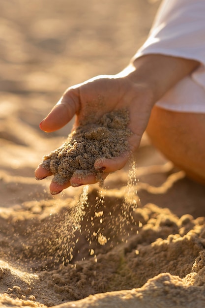 Vrouw bij het zand van de strandholding in haar hand