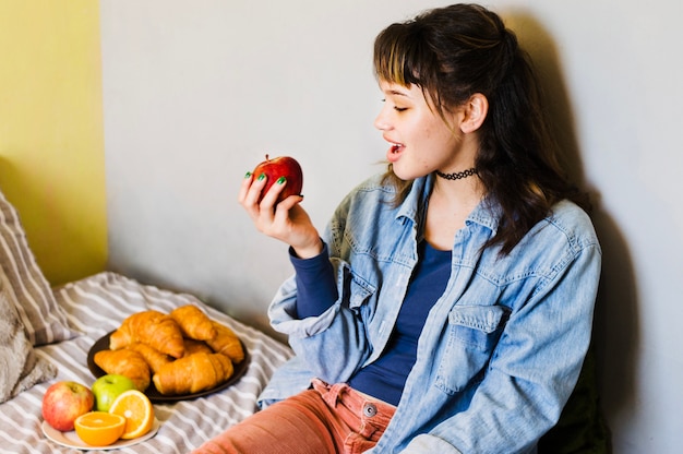 Gratis foto vrouw bijtend appel op bed