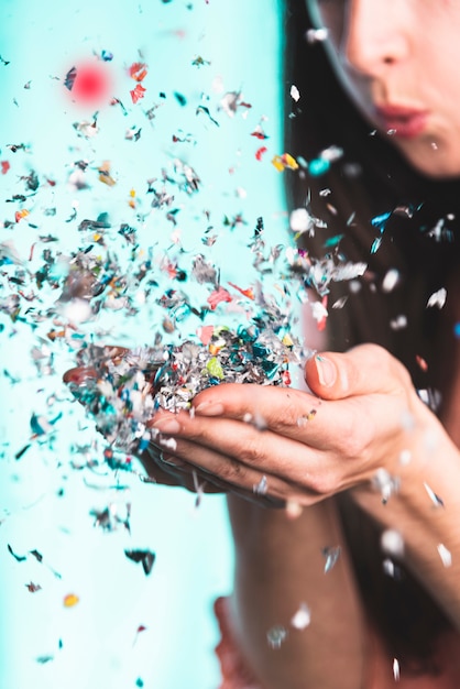 Gratis foto vrouw blaast confetti uit haar handen