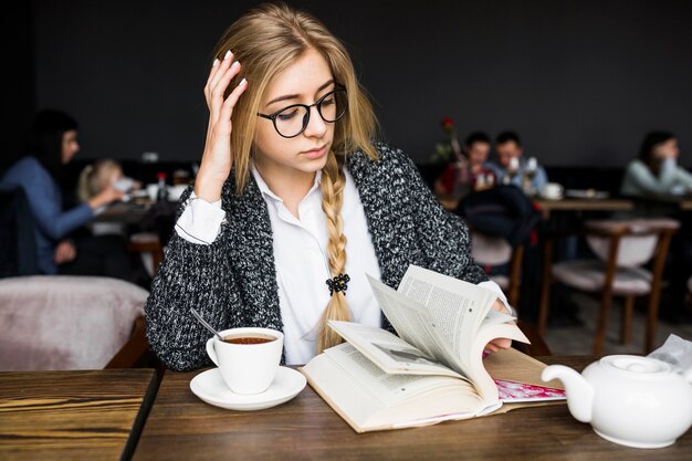 Vrouw boekpagina&#39;s in café draaien