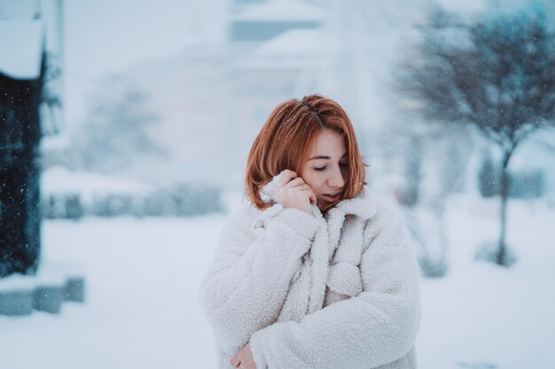 Vrouw buiten op sneeuwende koude de winterdag