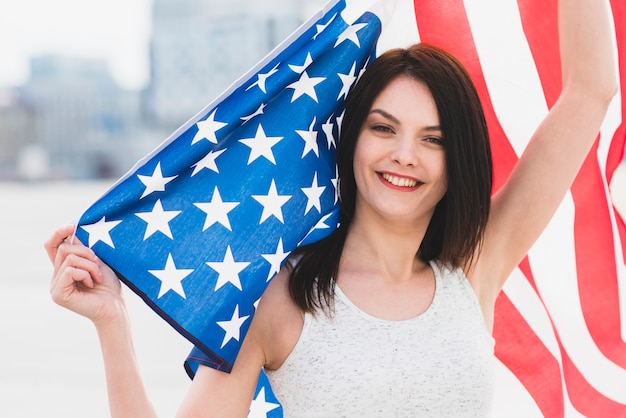 Vrouw camera kijken en glimlachen die brede Amerikaanse vlag golven