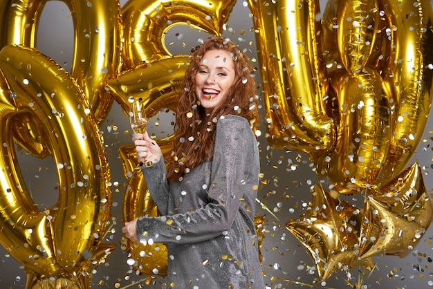 Vrouw champagne drinken onder de douche van confetti