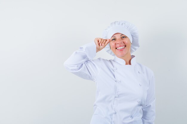 vrouw chef-kok die make-up in wit uniform doet en er mooi uitziet