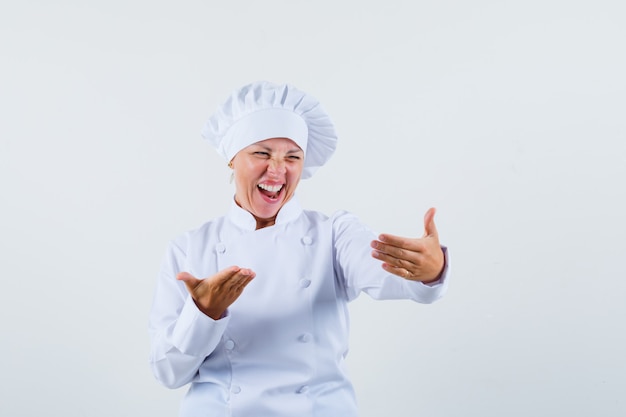 vrouw chef-kok die zich voordeed als lachen tijdens het kijken naar telefoon in wit uniform en op zoek geamuseerd
