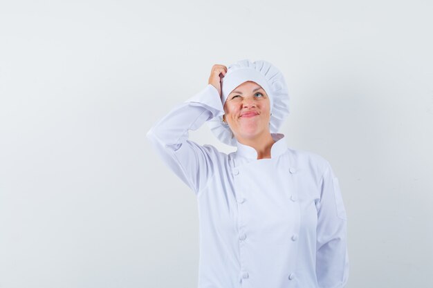 vrouw chef-kok in wit uniform hoofd krabben en op zoek vergeetachtig