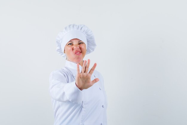 vrouw chef-kok in wit uniform stop gebaar tonen en op zoek verveeld