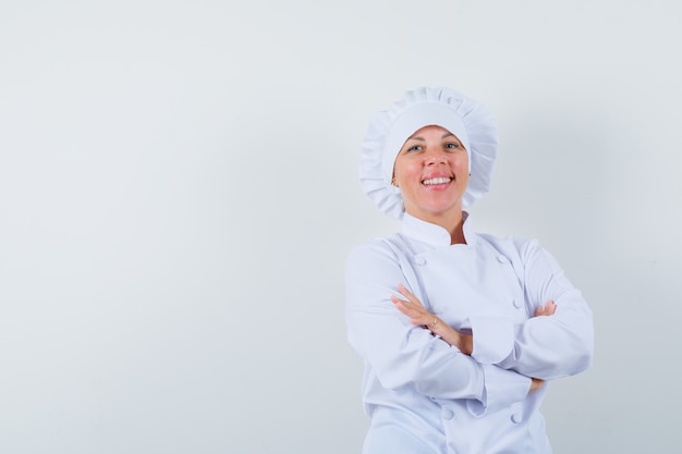 vrouw chef-kok permanent met gekruiste armen in wit uniform en op zoek zelfverzekerd