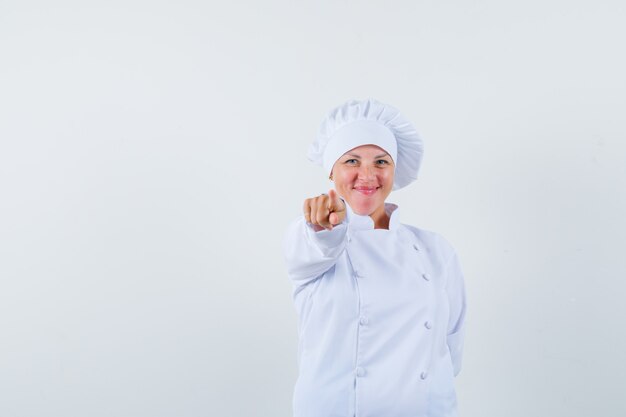 vrouw chef-kok wijst naar voren in wit uniform en kijkt blij