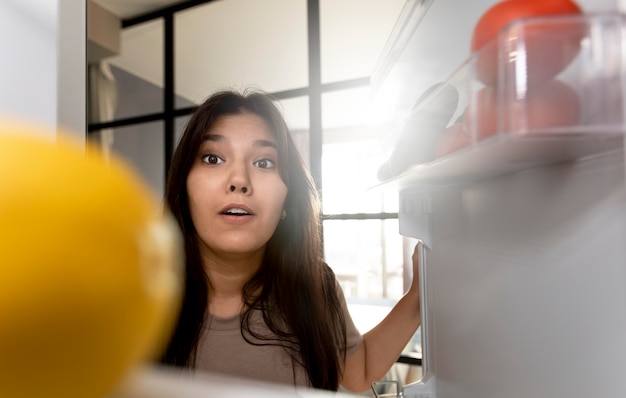 Vrouw controleert het interieur van haar koelkast thuis