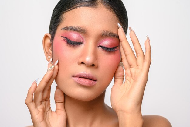 Vrouw deed roze make-up op en legde haar hand op haar gezicht geïsoleerd op wit