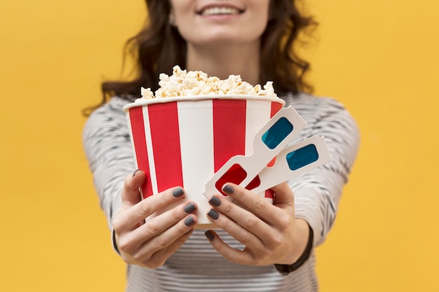 Vrouw die 3d glazen en emmer met popcorn houdt