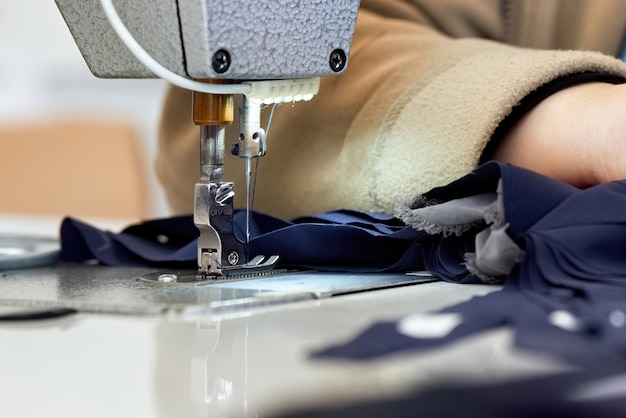 Vrouw die aan een naaimachine werkt met blauwe stof