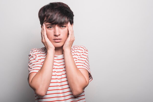 Vrouw die aan hoofdpijn lijdt die over witte achtergrond wordt geïsoleerd