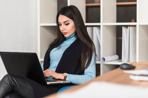 Vrouw die aan laptop in bureau werkt