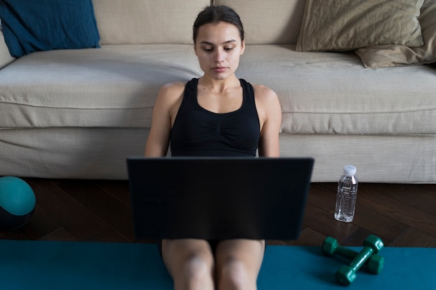 Gratis foto vrouw die aan laptop met gewichten naast haar werkt