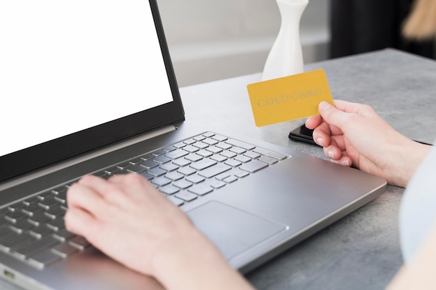 Vrouw die aan laptop werkt en creditcard houdt