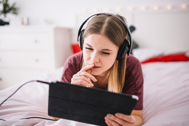 Vrouw die aan muziek en het doorbladeren van tablet luistert