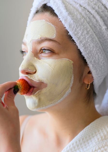 Vrouw die aardbei eet terwijl het dragen van gezichtsmasker