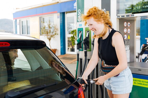 Vrouw die auto opvult en met de mens daarin lacht