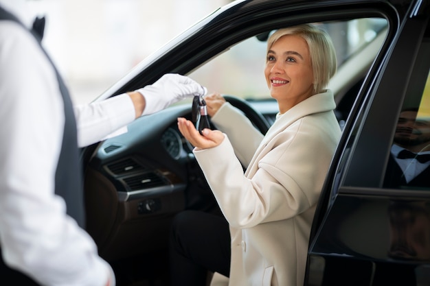 Vrouw die autosleutels uitwisselt met parkeerbediende