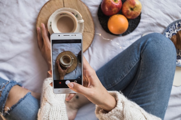 Gratis foto vrouw die beeld van koffie met smartphone neemt