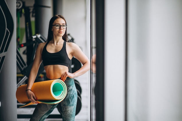 Gratis foto vrouw die bij de yogamat van de gymnastiekholding uitoefent