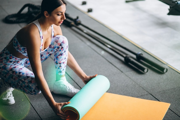 Gratis foto vrouw die bij de yogamat van de gymnastiekholding uitoefent