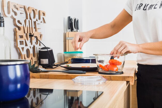 Vrouw die bij keuken tomaten in mixer zet