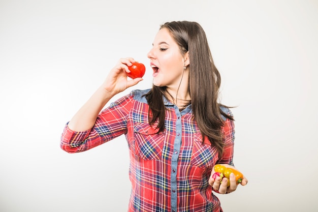 Gratis foto vrouw die bijt tomaat beweert