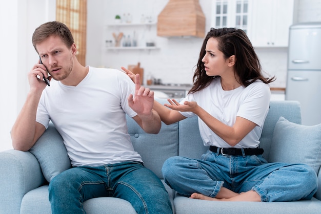 Vrouw die boos is terwijl haar vriendje aan de telefoon spreekt