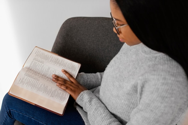 Vrouw die de bijbel binnenshuis leest