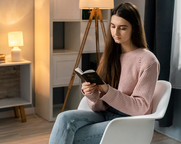 Vrouw die de bijbel leest terwijl u in stoel zit