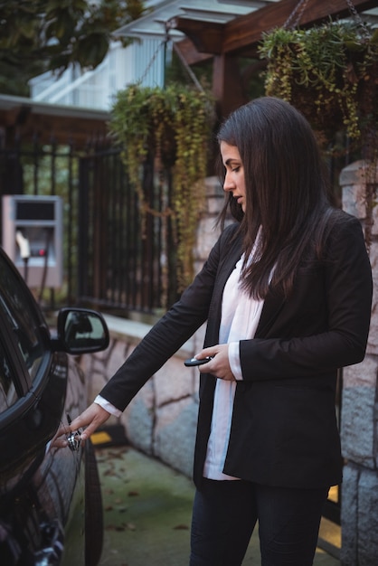 Vrouw die de deur van haar auto met afstandsbediening opent