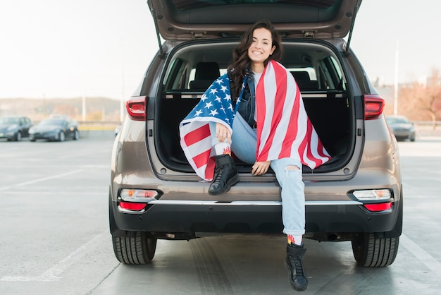 Vrouw die de grote vlag van de VS in autoboomstam draagt