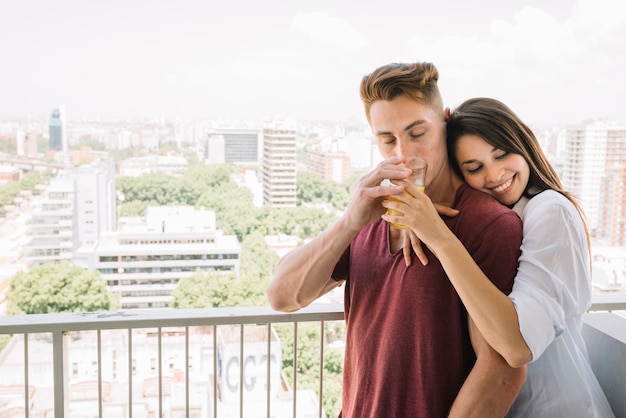 Gratis foto vrouw die de jonge mens met sapglas koestert op balkon