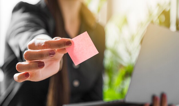 Vrouw die de kleverige nota met onscherpe achtergrond houdt