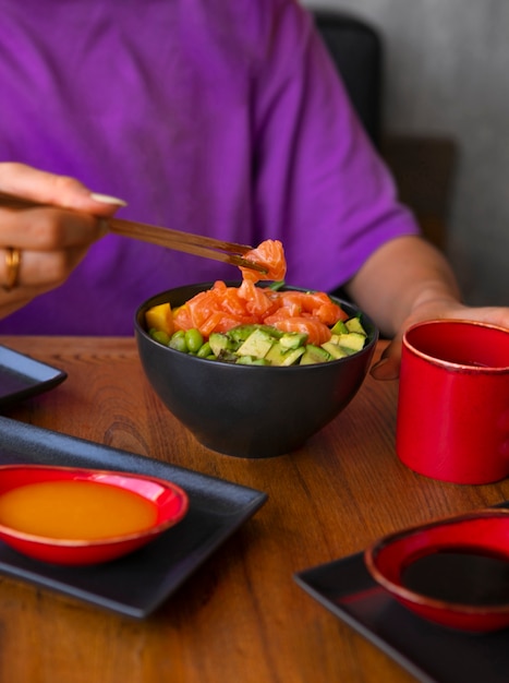 Gratis foto vrouw die de kom van de zalmschotel eet bij het restaurant