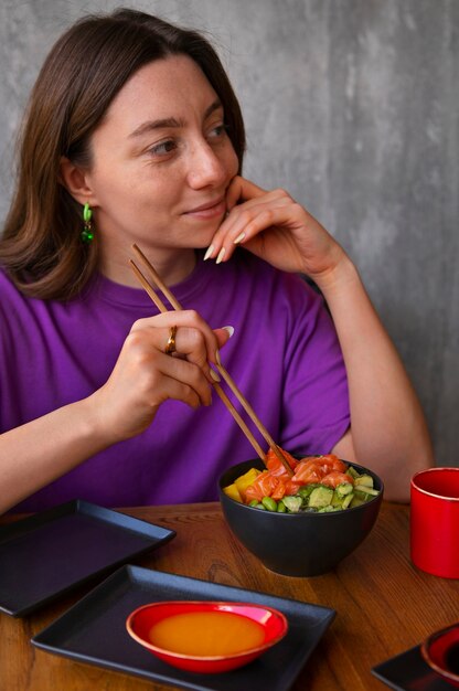 Vrouw die de kom van de zalmschotel eet bij het restaurant