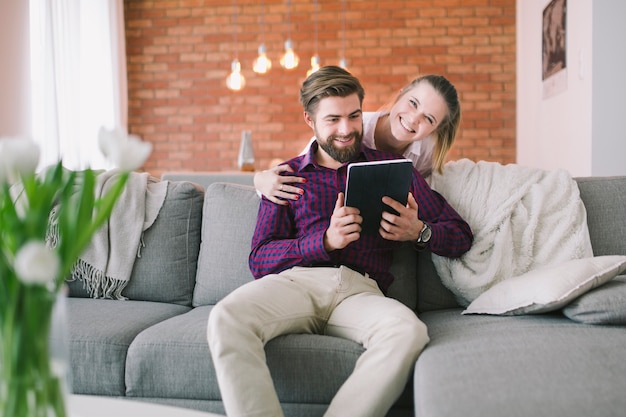 Gratis foto vrouw die de mens omhelst die tablet gebruikt