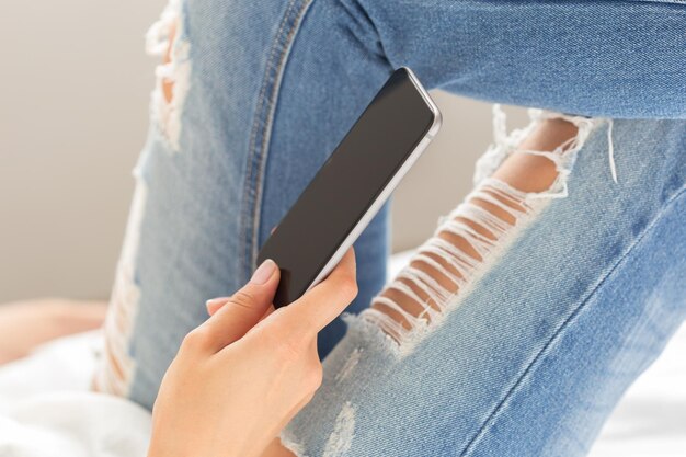 Vrouw die de mobiele telefoon op het bed controleert