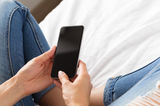 Vrouw die de mobiele telefoon op het bed controleert